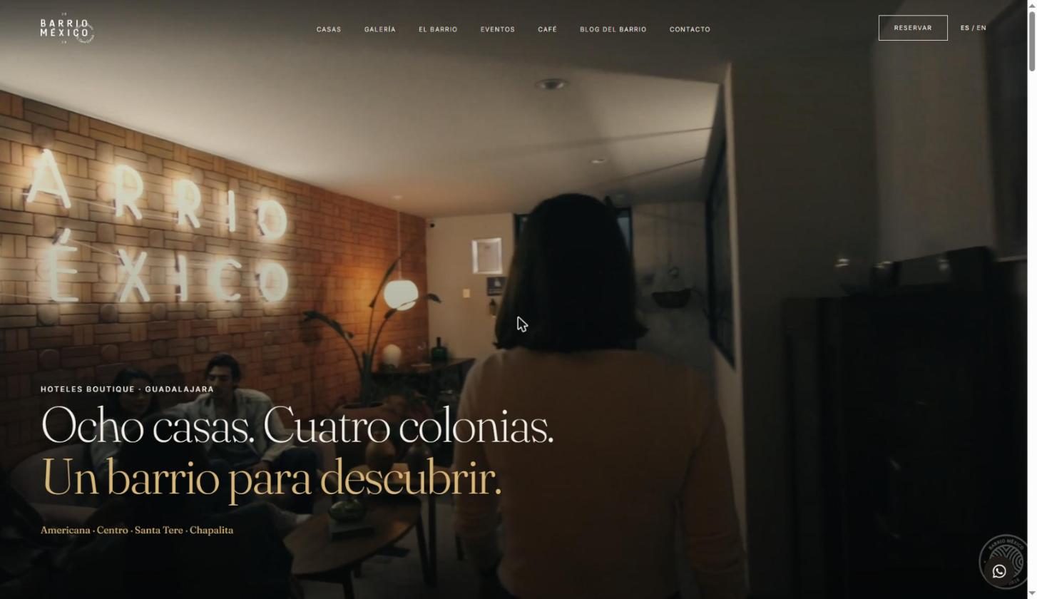 Barrio México home page: a dark full-bleed photo of a lounge with a neon Barrio México sign, the headline “Ocho casas. Cuatro colonias. Un barrio para descubrir.” in a light serif, and the four neighborhoods below.